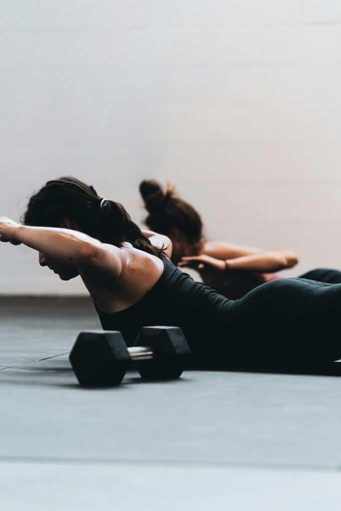 A group of adults exercising together on mats in a bright indoor community gym.