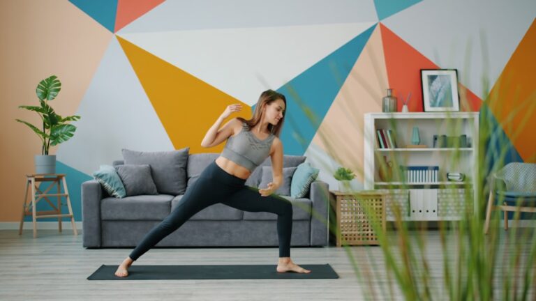 A person doing squats on a yoga mat in a living room with natural light and minimal exercise equipment visible.