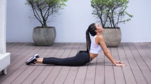 Three adults performing gentle stretches together inside a bright, comfortable living room.